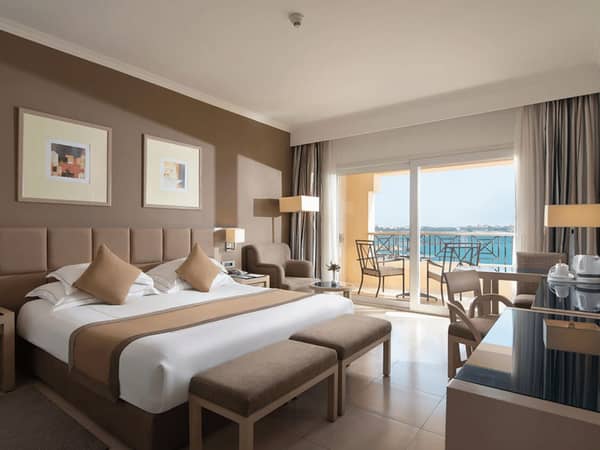 Luxurious Cleopatra Premium Deluxe Room with a king-sized bed, modern seating area, and private balcony overlooking the sea.