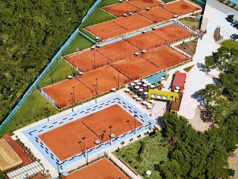 Aerial view of Corendon Gallery's clay tennis courts and adjacent leisure area with seating.