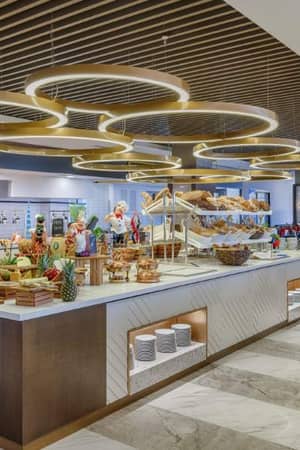 Buffet area in a modern dining space with various food items, stylish lighting, and a contemporary design at Corendon.