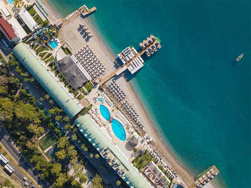 Aerial view of Corendon Playa Kemer resort with swimming pools, sun loungers, and private beach along the Mediterranean Sea.