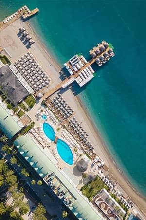 Aerial view of Corendon Playa Kemer resort with swimming pools, sun loungers, and private beach along the Mediterranean Sea.