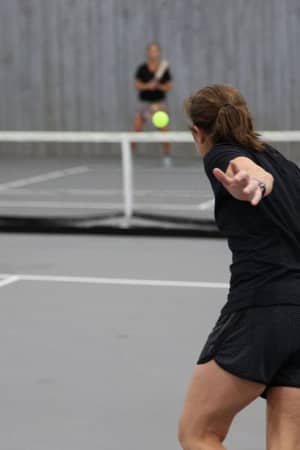Four players engaging in a pickleball game on an indoor court, with one player poised to return the ball.