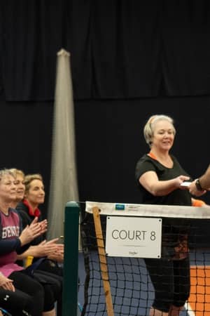 Tennis coach distributing refreshments to female players on a bench at Cheshire Oaks.