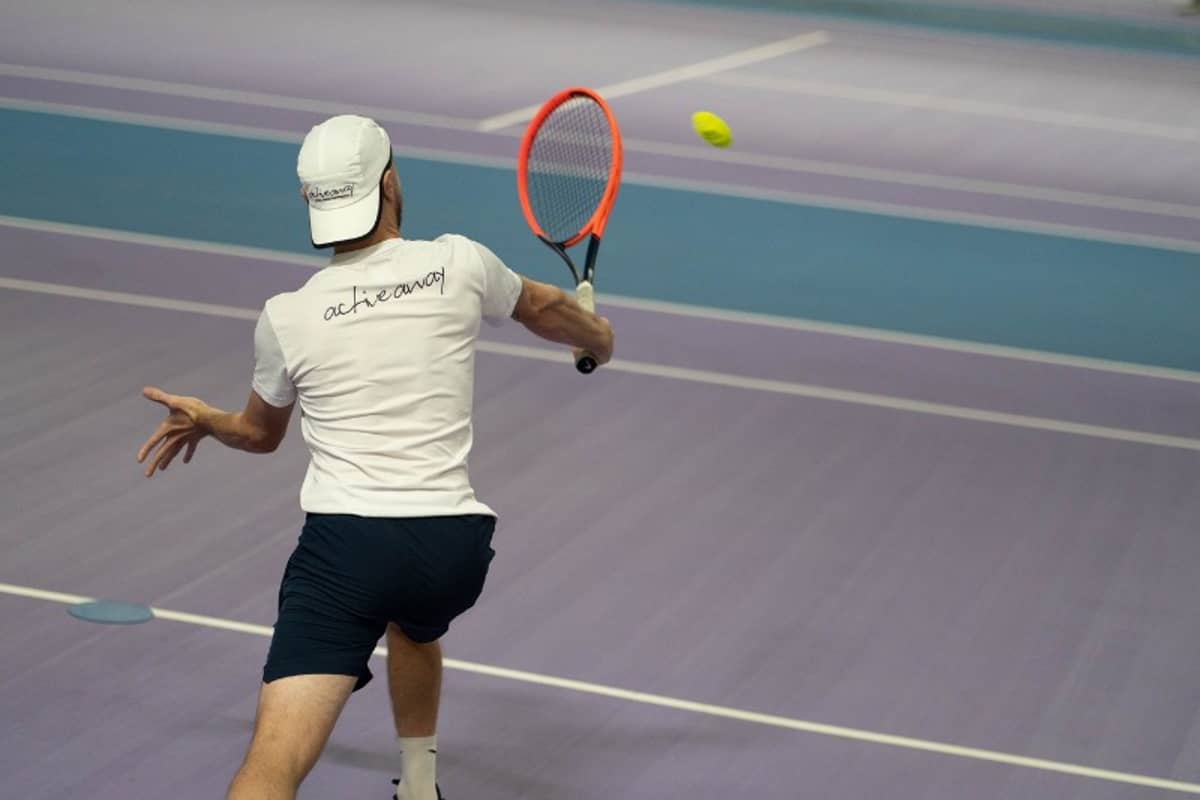 Tennis coach hitting a backhand shot with an orange racquet on indoor courts at DL Chorley.