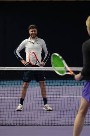 Tennis coach instructing a student during a practice session at DL Chorley Gallery indoor court.