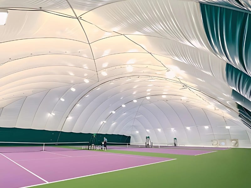Indoor tennis court at DL Woking with a large inflated dome ceiling and green and purple flooring.