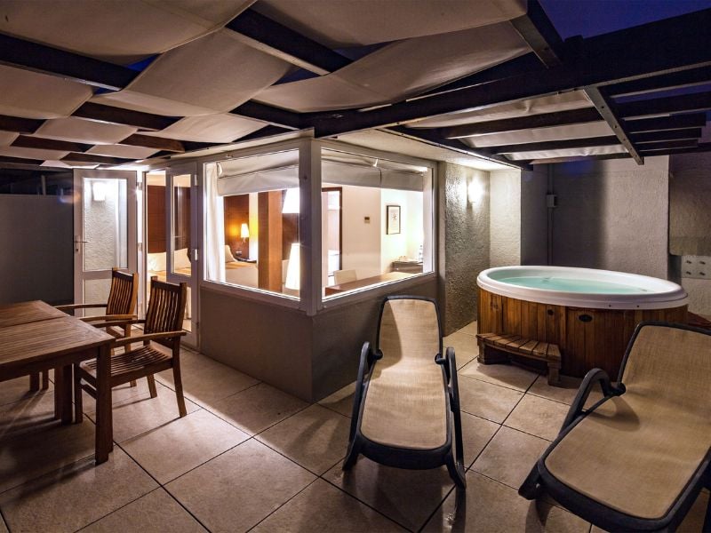 Luxury veranda with private hot tub, wooden seating, and ambient evening lighting at Dom Pedro Gallery.
