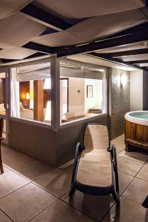 Luxury veranda with private hot tub, wooden seating, and ambient evening lighting at Dom Pedro Gallery.