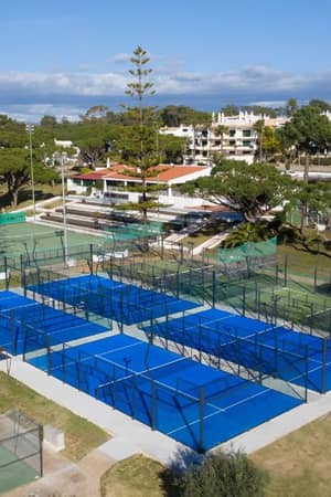 Aerial view of blue padel courts at Dona Filipa, surrounded by green areas and neighbouring tennis courts.
