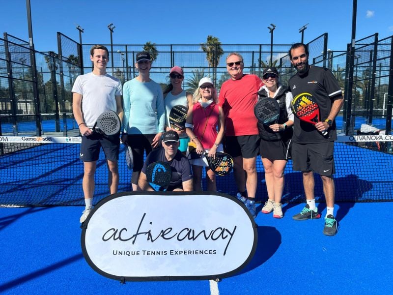 Group photo of nine people on a padel court at Dona Filipa, holding rackets with an Active Away banner in front.