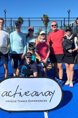 Group photo of nine people on a padel court at Dona Filipa, holding rackets with an Active Away banner in front.