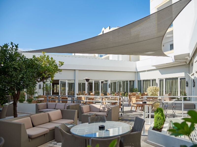 Outdoor dining area at Dona Filipa Hotel with rattan furniture and a contemporary canopy.