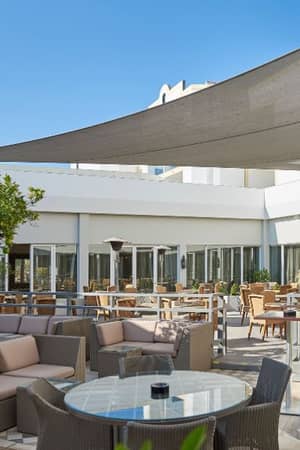 Outdoor dining area at Dona Filipa Hotel with rattan furniture and a contemporary canopy.