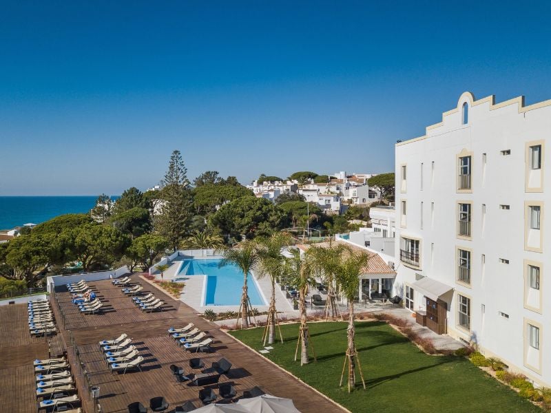 Aerial view of Dona Filipa hotel pool area with sun loungers and ocean backdrop.