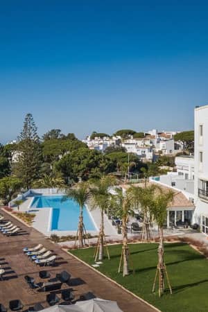 Aerial view of Dona Filipa hotel pool area with sun loungers and ocean backdrop.