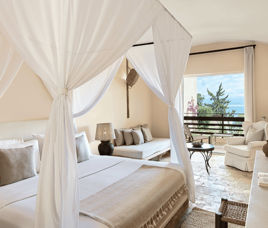 Interior of Daphnila Bungalow at Daphnila Bay with a canopy bed and a sea view from the window.