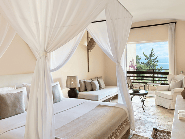 Interior of Daphnila Bungalow at Daphnila Bay with a canopy bed and a sea view from the window.