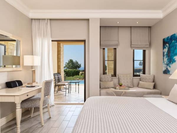 Deluxe double room with elegant decor, a private pool terrace, and views of a golf course and sea in the background.