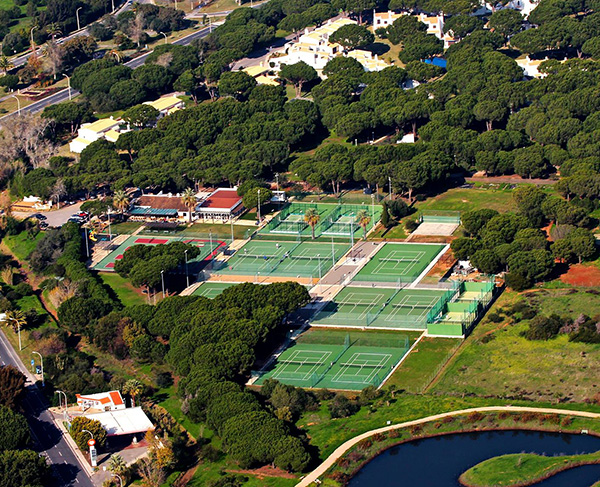 Aerial view of Dom Pedro Vilamoura with multiple tennis courts amidst green surroundings.