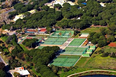 Aerial view of Dom Pedro Vilamoura with multiple tennis courts amidst green surroundings.