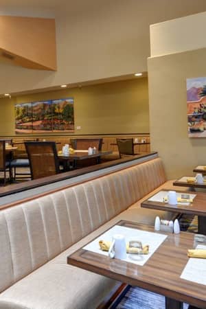 Dining area at El Conquistador Gallery featuring set tables with yellow napkins and wall art, creating a warm ambiance.