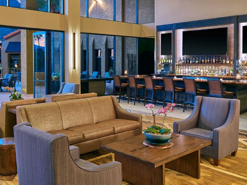 Indoor view of El Conquistador Gallery Restaurant with a modern bar, sofas, armchairs, and decorative lighting.