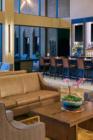 Indoor view of El Conquistador Gallery Restaurant with a modern bar, sofas, armchairs, and decorative lighting.