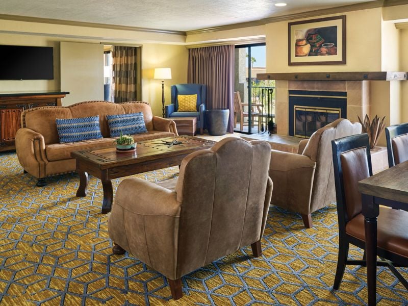 Luxurious hotel living area at El Conquistador with sofas, armchairs, a flat-screen TV, fireplace, and southwestern decor.