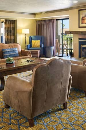 Luxurious hotel living area at El Conquistador with sofas, armchairs, a flat-screen TV, fireplace, and southwestern decor.