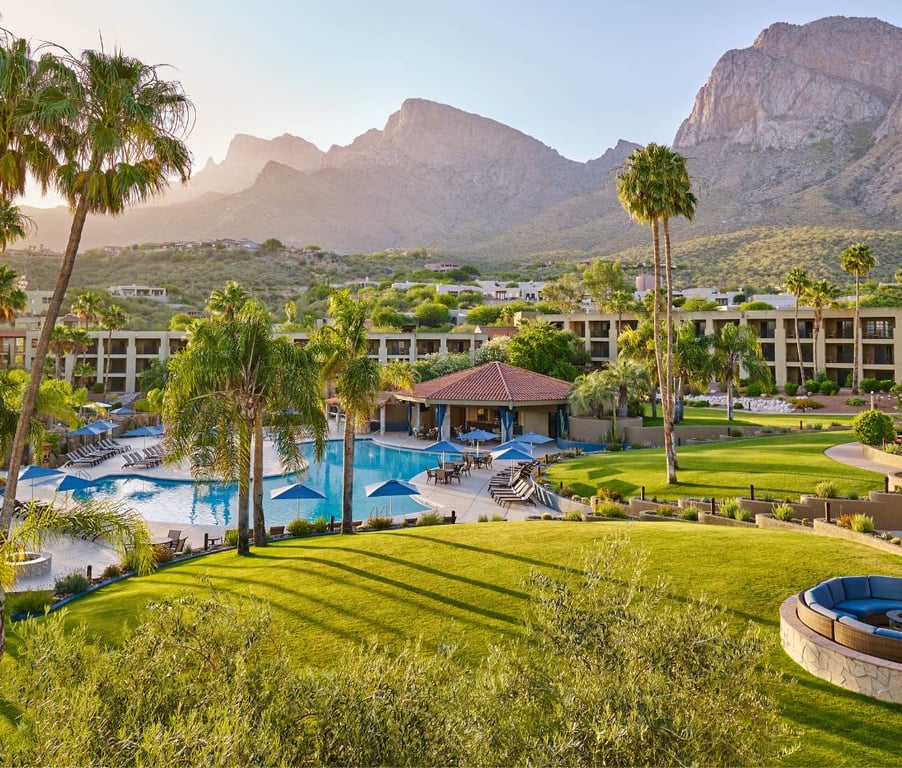 El Conquistador Resort featuring a large pool with sun loungers, surrounded by palm trees, against a backdrop of mountains.