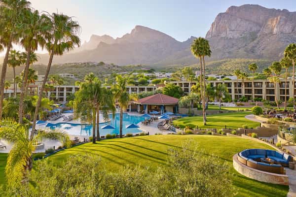 View of El Conquistador Resort with swimming pools, green lawns, and desert mountains in Tucson, Arizona.