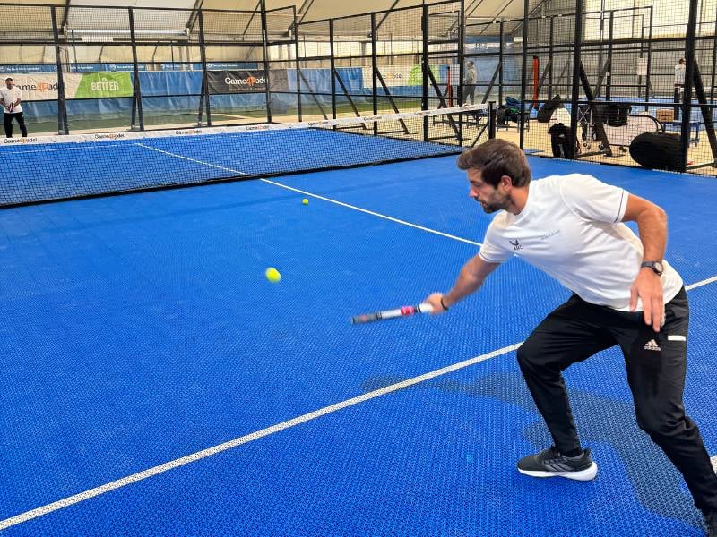 Coach playing paddle tennis on an indoor court at Gosling Sports Park, focused on returning the ball.