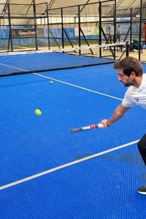 Coach playing paddle tennis on an indoor court at Gosling Sports Park, focused on returning the ball.