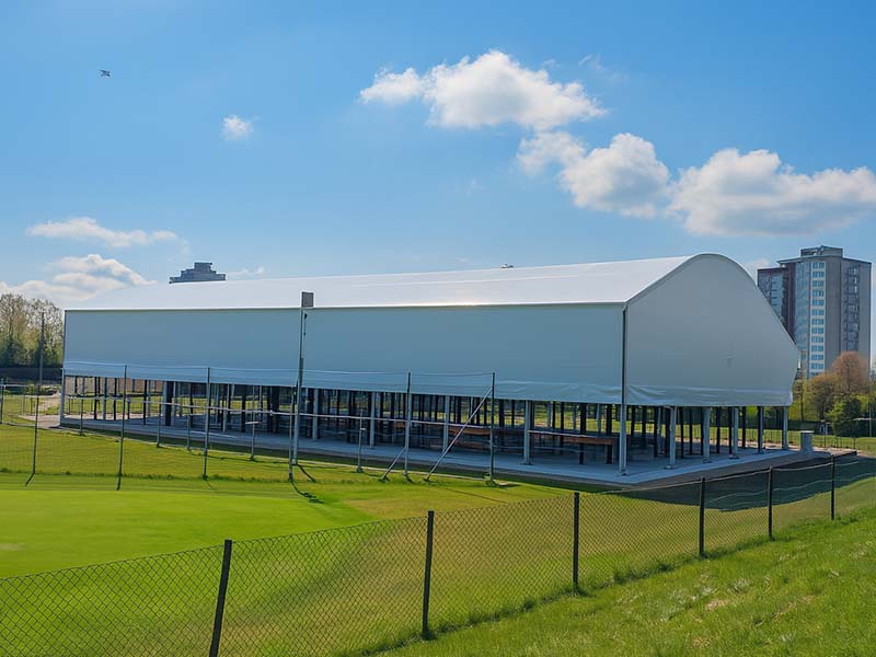 Outdoor padel sports facility at Great Western Golf with a large covered structure and green surroundings, backed by high-rise buildings.