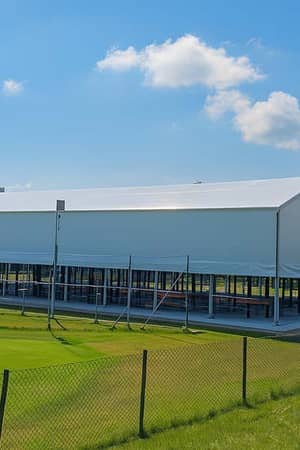 Outdoor padel sports facility at Great Western Golf with a large covered structure and green surroundings, backed by high-rise buildings.