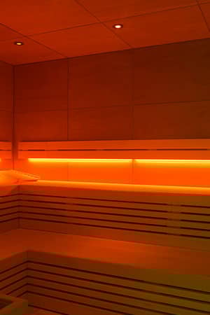 Sauna room at Hipotels Barosa Park with wooden benches and warm orange lighting.