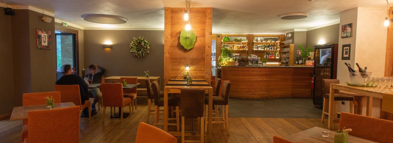 Cosy bar at Hotel Cristallo with wooden accents, ambient lighting, plush orange chairs, and a well-stocked drinks display.