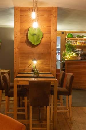 Cosy bar at Hotel Cristallo with wooden accents, ambient lighting, plush orange chairs, and a well-stocked drinks display.