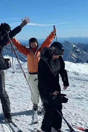 Group of skiers cheerfully posing on a snowy mountain slope near Hotel Cristallo under a clear sky.
