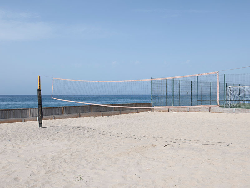 Sandy beach volleyball court with a net by the sea at Hotel Impressive Playa Granada.