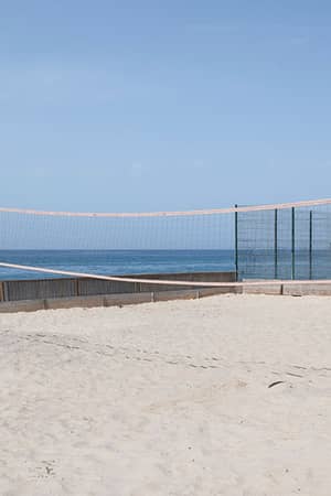 Sandy beach volleyball court with a net by the sea at Hotel Impressive Playa Granada.