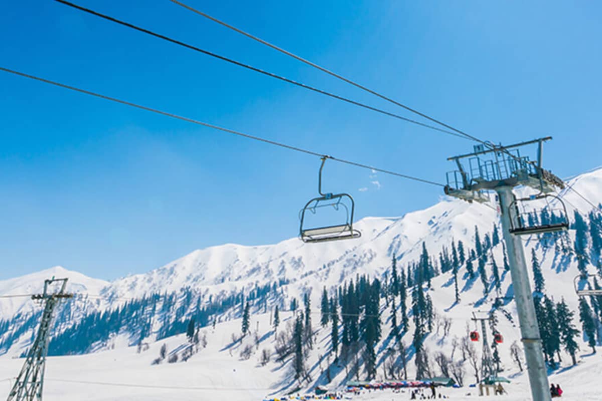 Ski lifts and snow-covered mountains with pine trees at Hotel Monterosa, under a clear blue sky.
