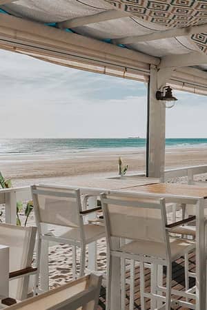 Beachfront restaurant terrace at Hotel Vincci Costa Golf with white furniture overlooking the sandy beach and ocean.