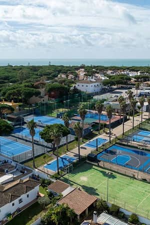 Aerial view of tennis courts at Hotel Vincci Costa Golf with ocean in the background.
