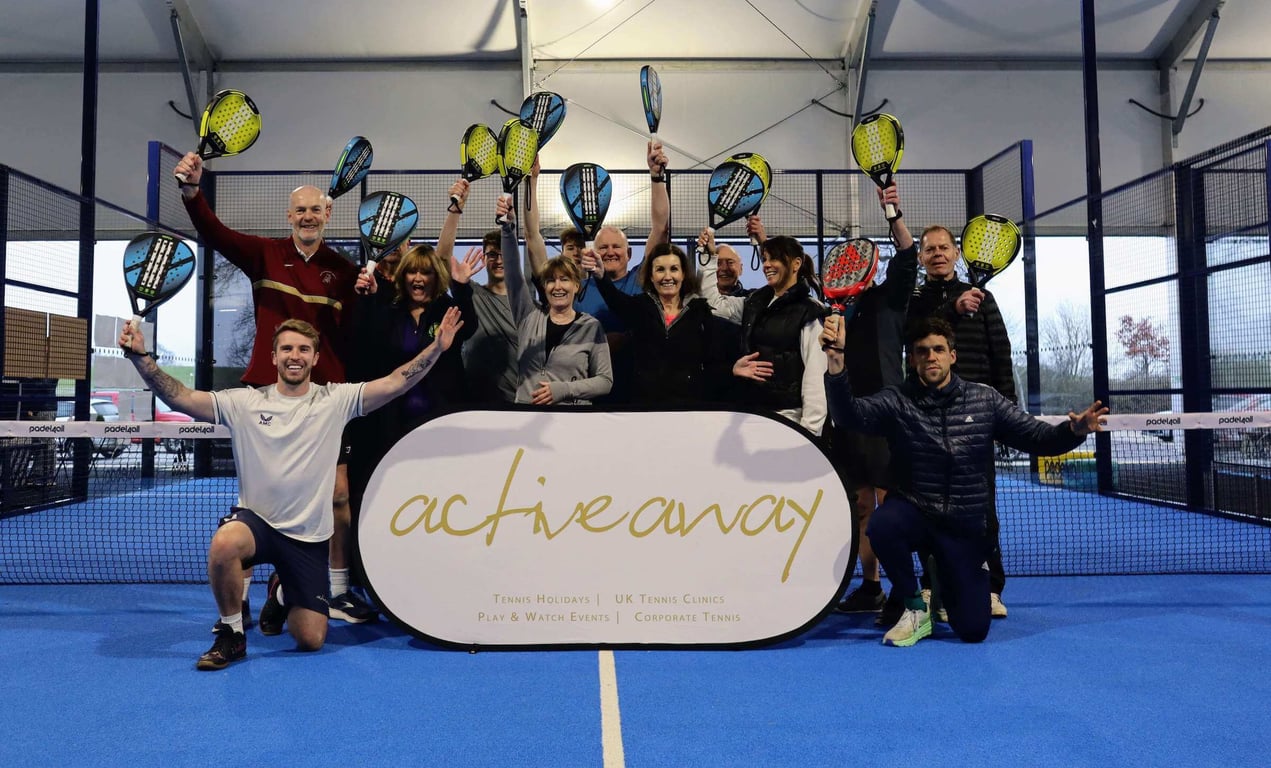 Group of people celebrating with rackets on a padel court under a tent, featuring an Active Away banner.