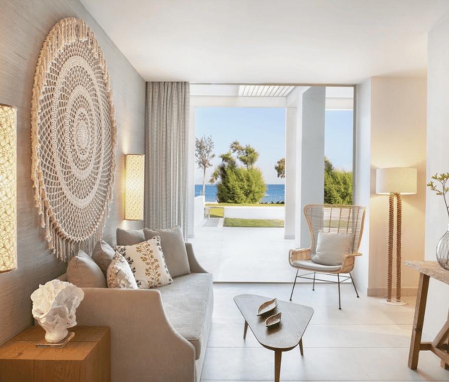Interior of Ikos Aria Deluxe One Bedroom Bungalow Suite with modern decor and beachfront view.