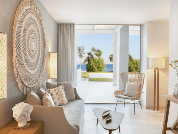 Interior of Ikos Aria Deluxe One Bedroom Bungalow Suite with modern decor and beachfront view.