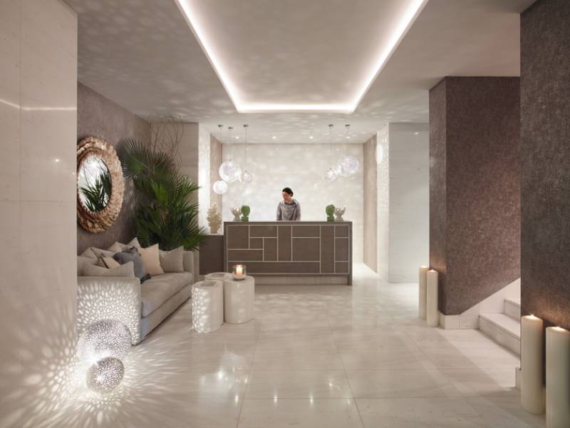 Ikos Aria spa reception area with modern decor, ambient lighting, and green plants.