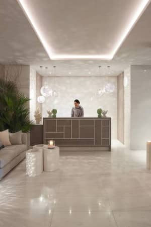 Ikos Aria spa reception area with modern decor, ambient lighting, and green plants.