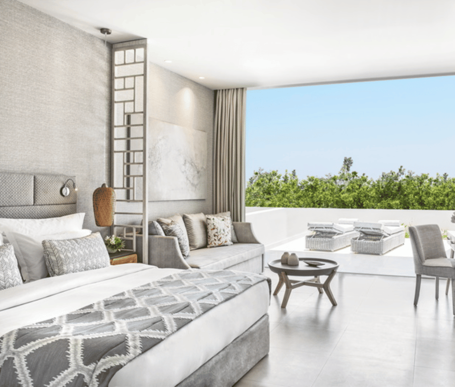 Luxurious junior suite at Ikos Aria with a private garden and garden view, featuring a spacious bedroom, elegant decor, and outdoor seating area.